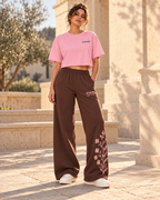 Idea de combinación: vista frontal con modelo, camiseta corta ZOMKI Brilla sin miedo rosa y pantalón Soft Rebel chocolate con flores. Cada prenda se vende por separado. Imagen generada con IA.