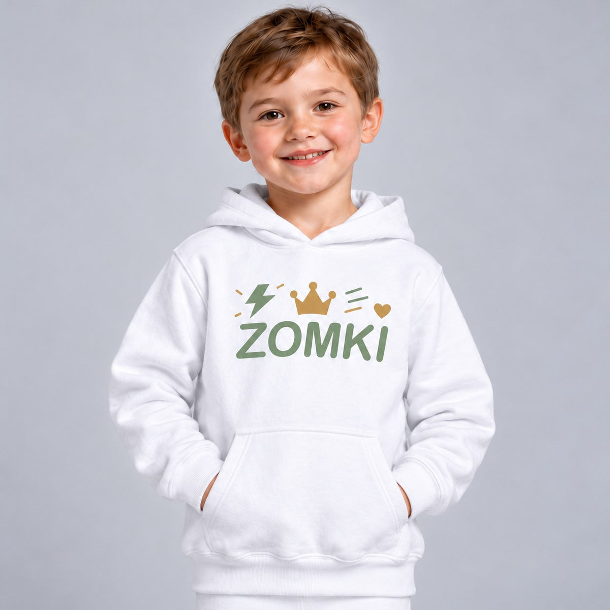 Modelo infantil sintético con sudadera blanca ZOMKI Corona Verde salvia: logotipo con corona, corazón, rayo y trazos de energía. Se vende solo la sudadera. Imagen generada con IA.