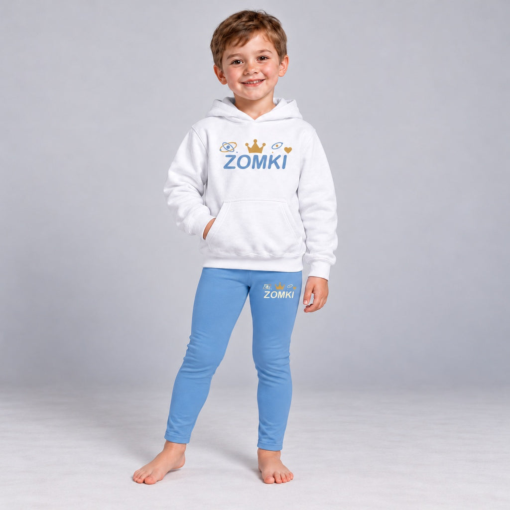 Visualización editorial generada con IA con el mismo modelo infantil sintético del conjunto ZOMKI Corona Azul, en una pose nueva de postura asimétrica. Sudadera blanca y leggings coordinados con órbitas y pequeños puntos. No representa a una persona real.