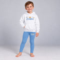 Visualización editorial generada con IA con el mismo modelo infantil sintético del conjunto ZOMKI Corona Azul, en una pose nueva de postura asimétrica. Sudadera blanca y leggings coordinados con órbitas y pequeños puntos. No representa a una persona real.