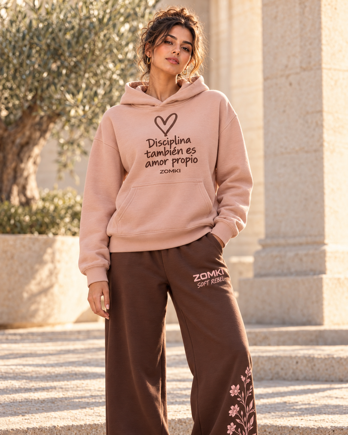 Idea de combinación: modelo con sudadera ZOMKI Disciplina también es amor propio rosa y pantalón Soft Rebel chocolate con flores. Cada prenda se vende por separado. Imagen generada con IA.