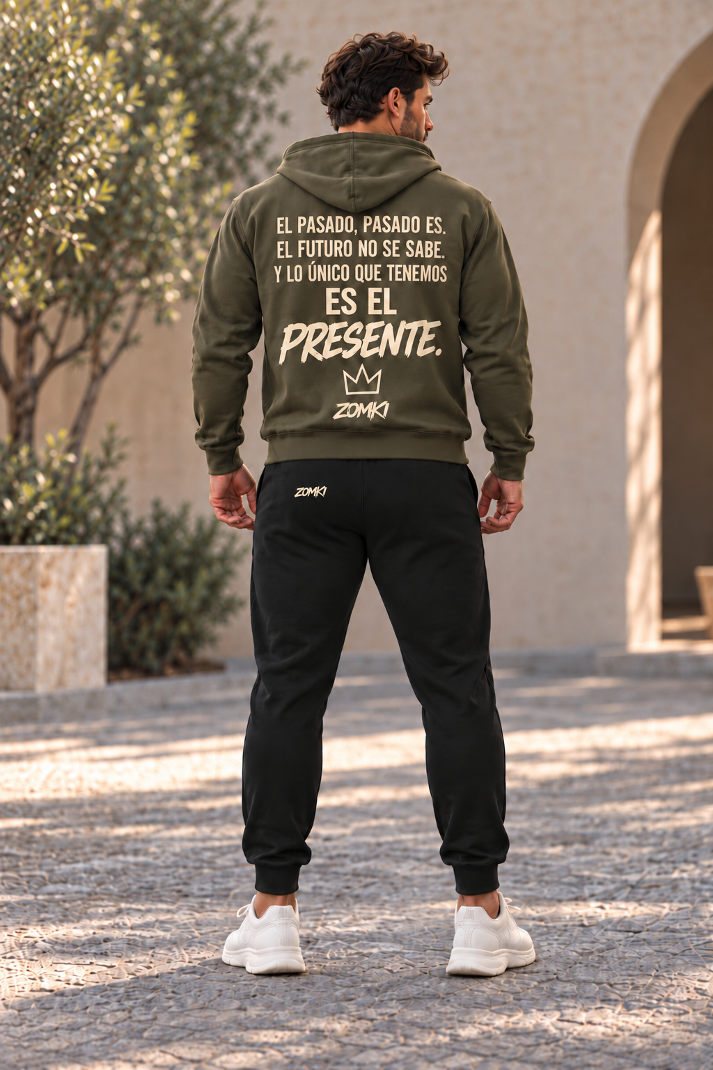 Modelo de espaldas con sudadera ZOMKI El Presente oliva y jogger negro; firma trasera del pantalón en el lado izquierdo. Cada prenda se vende por separado. Imagen generada con IA.