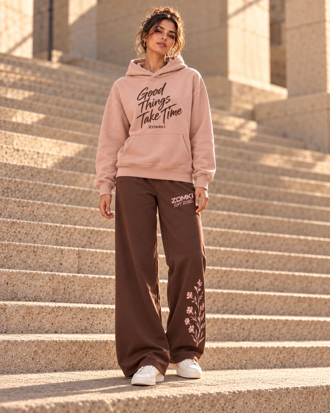 Idea de combinación: modelo con sudadera ZOMKI Good Things Take Time rosa y pantalón Soft Rebel chocolate con flores. Cada prenda se vende por separado. Imagen generada con IA.