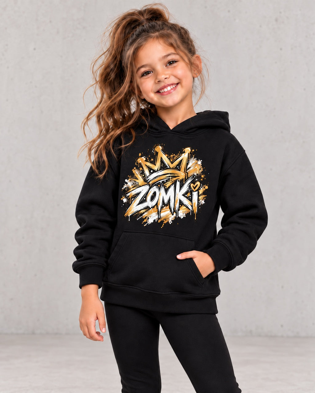 Modelo sintético generado con IA: sudadera infantil ZOMKI Graffiti Dorado negra; vista con niña, prenda suelta
