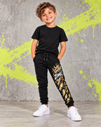 Jogger juvenil ZOMKI Graffiti Dorado · Negro, en modelo masculino oficial ZOMKI. Se vende únicamente esta prenda. Imagen creada con IA; maquetas de producto en galería.