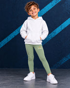 Leggings infantiles ZOMKI Corona · Verde salvia, en modelo masculino oficial ZOMKI. Se vende únicamente esta prenda. Imagen creada con IA; maquetas de producto en galería.