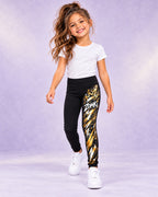 Leggings infantiles ZOMKI Graffiti Dorado · Negro, en modelo femenina oficial ZOMKI. Se vende únicamente esta prenda. Imagen creada con IA; maquetas de producto en galería.