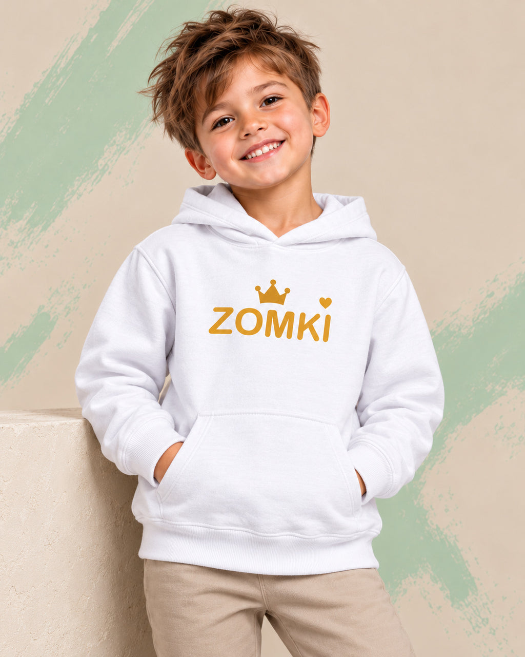 Sudadera infantil ZOMKI Corona · Blanca y mostaza, en modelo masculino oficial ZOMKI. Se vende únicamente esta prenda. Imagen creada con IA; maquetas de producto en galería.