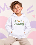 Sudadera infantil ZOMKI Corona · Blanca y salvia, en modelo masculino oficial ZOMKI. Se vende únicamente esta prenda. Imagen creada con IA; maquetas de producto en galería.