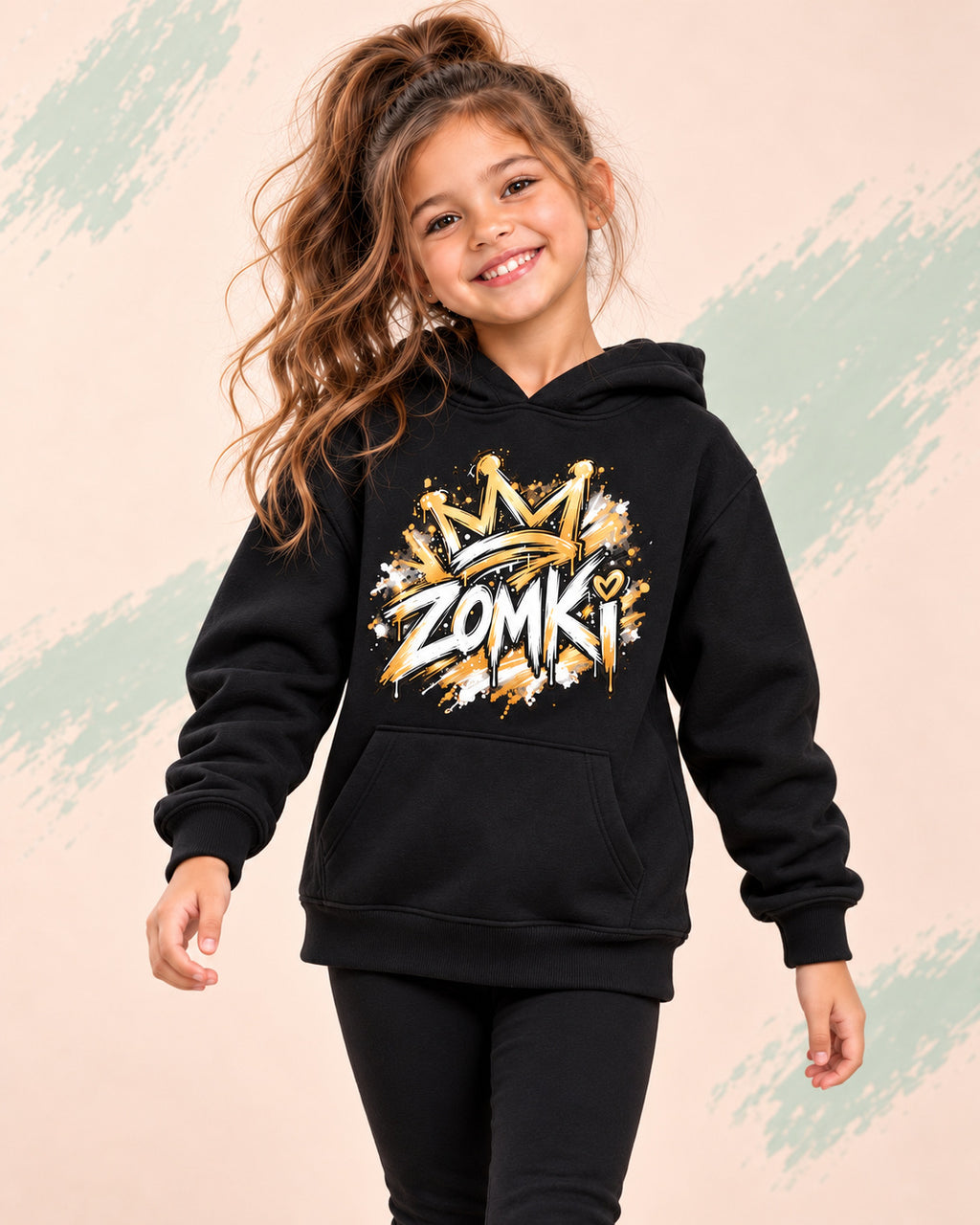 Sudadera infantil ZOMKI Graffiti Dorado · Negra, en modelo femenina oficial ZOMKI. Se vende únicamente esta prenda. Imagen creada con IA; maquetas de producto en galería.