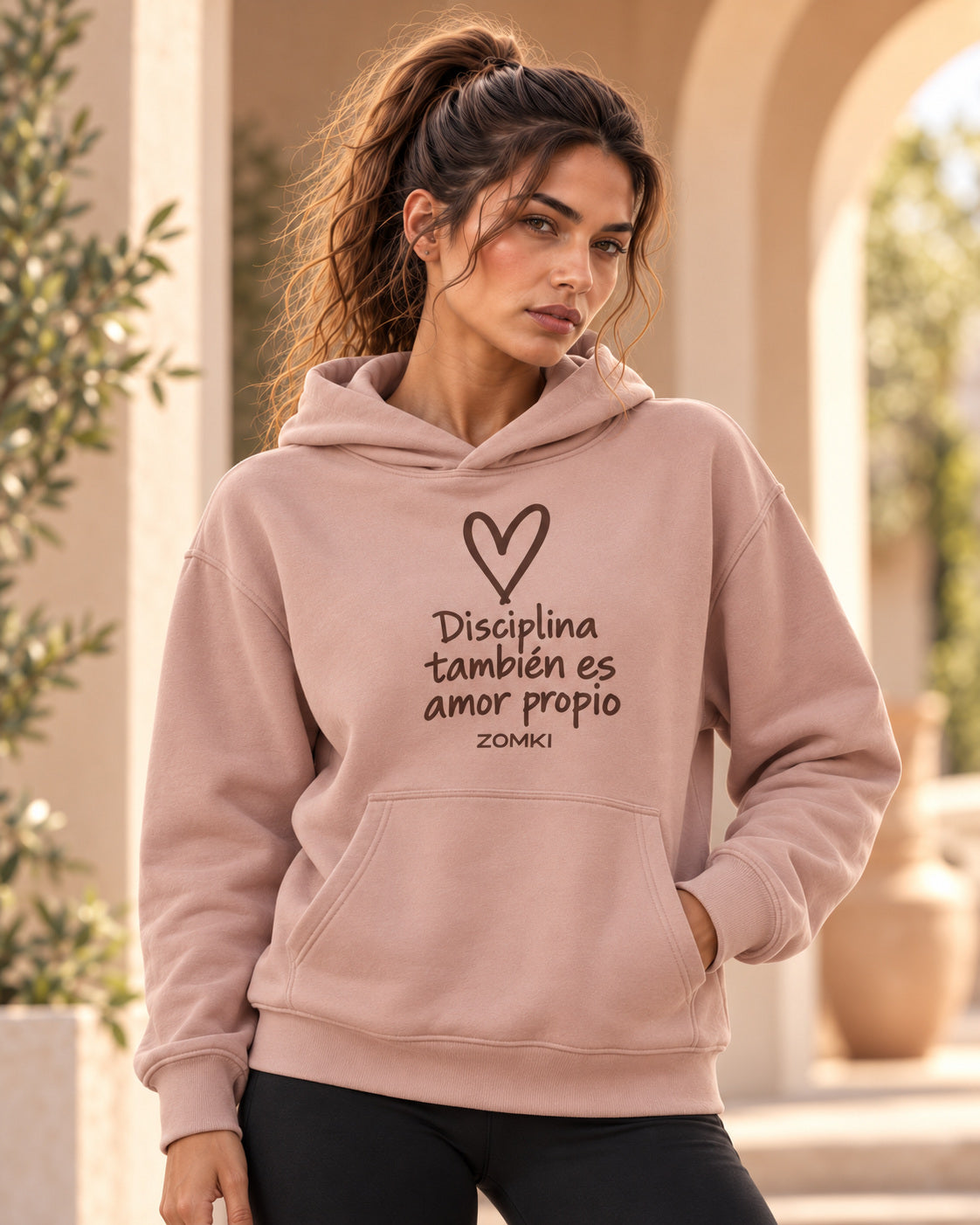 Sudadera ZOMKI Disciplina también es amor propio · Rosa empolvado, en modelo femenina oficial ZOMKI. Se vende únicamente esta prenda. Imagen creada con IA; maquetas de producto en galería.
