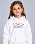 Modelo con Sudadera infantil ZOMKI Corona · Blanca y lavanda. Se venden únicamente la sudadera. Encuadre individual de la prenda. Imagen generada con IA.