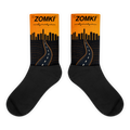 Calcetines ZOMKI Road Running Sunset: caña naranja con skyline y carretera, pie negro. Maqueta oficial de Printful.